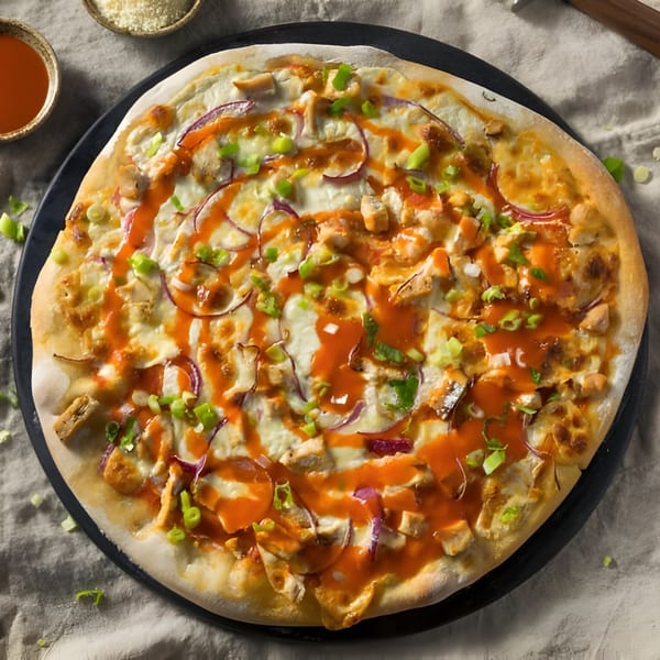 Zee's Kitchen's Buffalo Chicken Pizza, topped with red onion, green onion, and hot sauce.